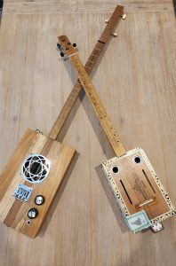 Two cigar box guitars on a table.