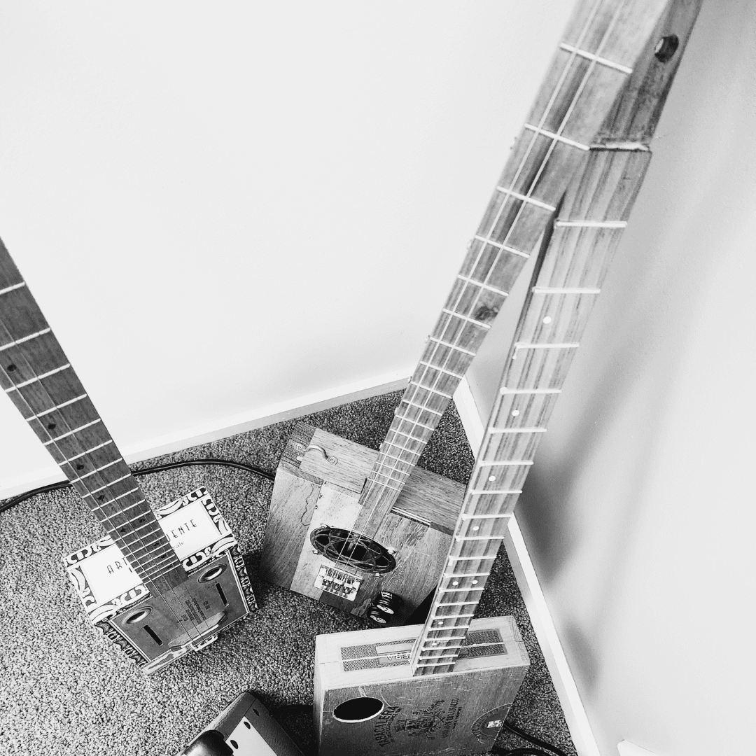 Three string cigar box guitars leaning on a wall.